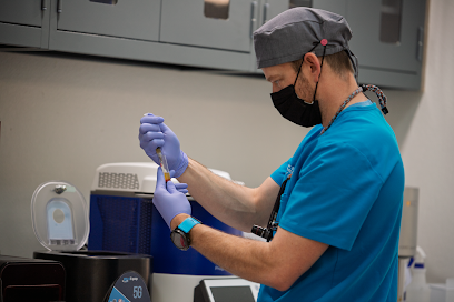 Dental professional in blue scrubs preparing a dental instrument